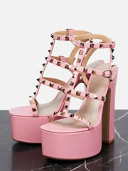 Pink platform sandals with studded details on a marble surface