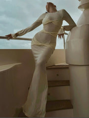 Person wearing a sheer, long-sleeve dress on a boat with a cloudy sky background