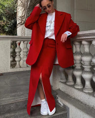 Person wearing a red suit with a white shirt and sneakers, standing on stone steps.
