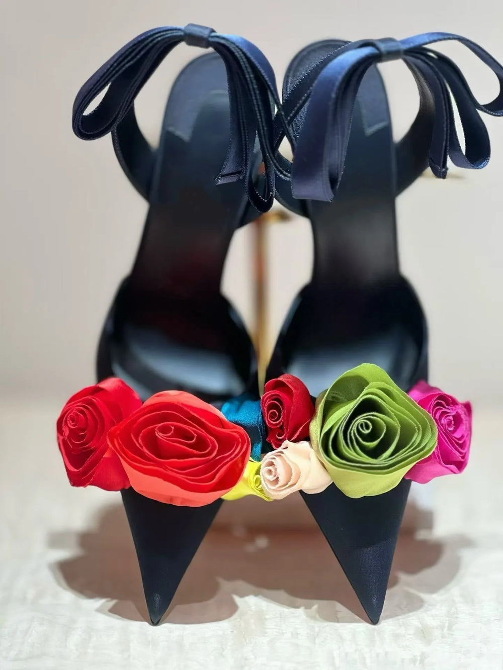 Front view of dark blue stiletto heels adorned with a colorful array of fabric roses.