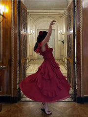 A woman posing in a flowing red dress with layered ruffles, accentuating the elegant silhouette.