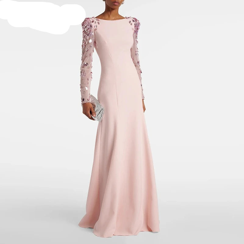 Pink evening gown with floral embellishments on sleeves, held by a model against a white background, featuring the brand 'TwoTwinStyle'.