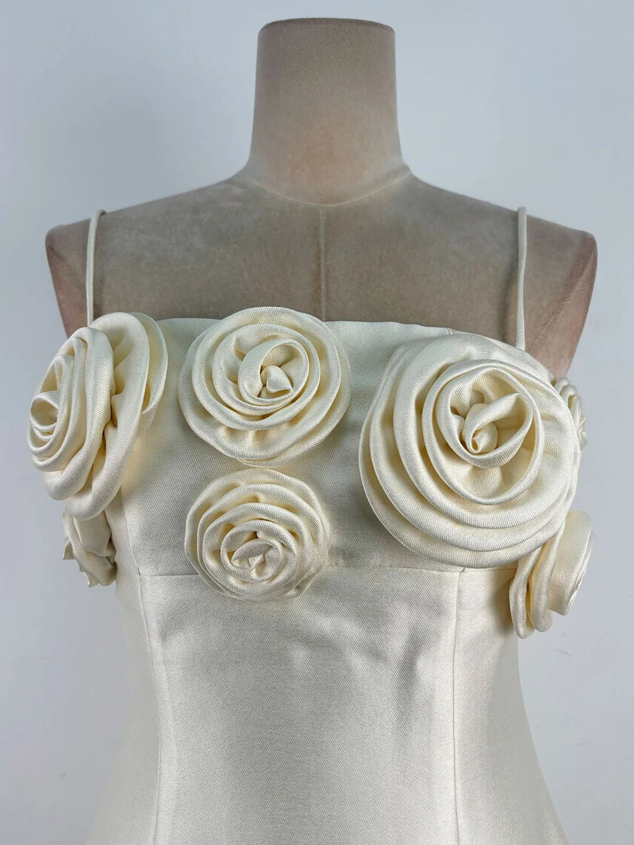 Mannequin wearing a cream-colored dress with floral embellishments on a plain background