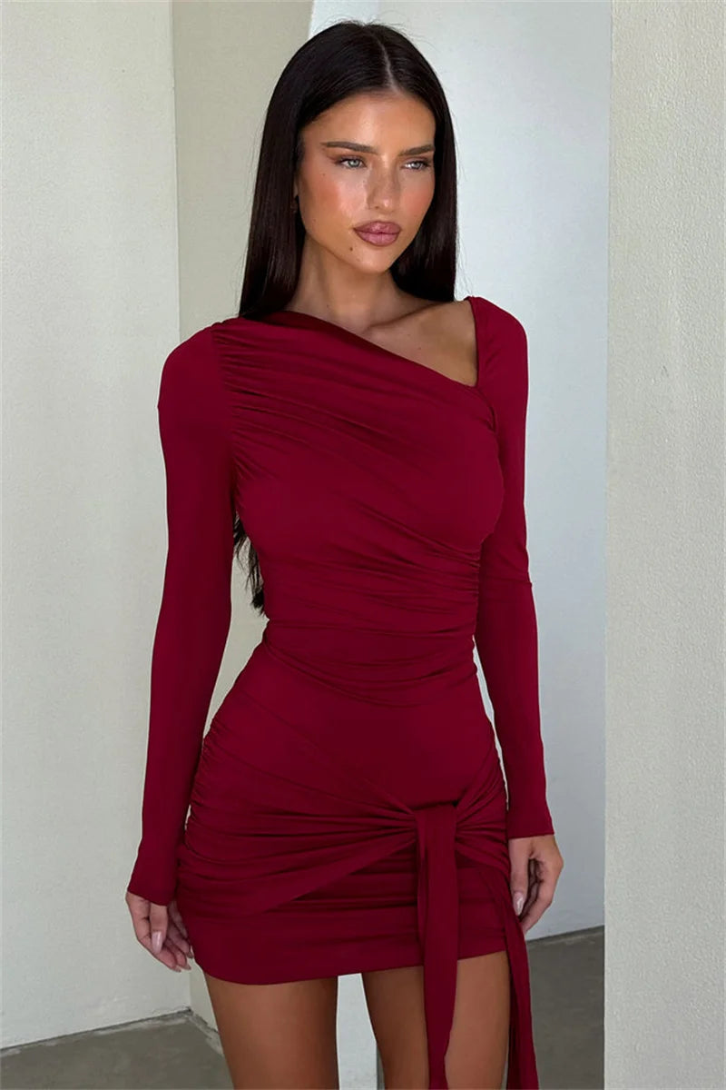 Woman wearing a burgundy dress with long sleeves against a plain background