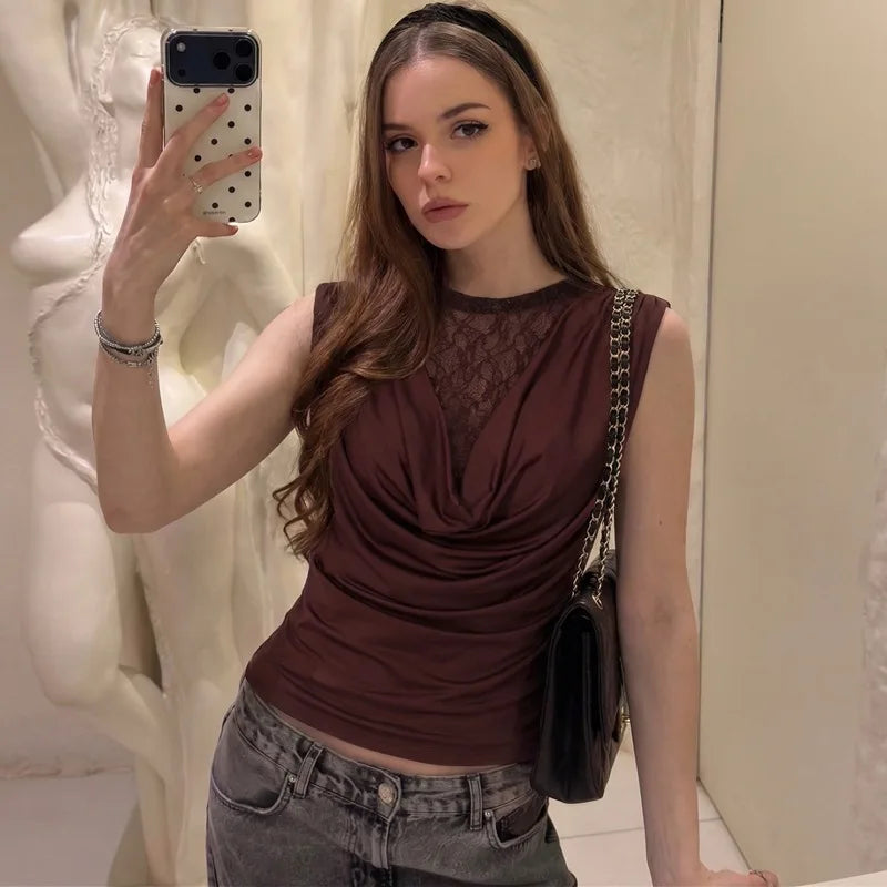 Woman taking a mirror selfie wearing a brown top and gray jeans, holding a phone with a polka dot case.