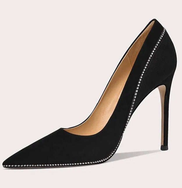 Black high-heeled shoe with studded details on a light gray background