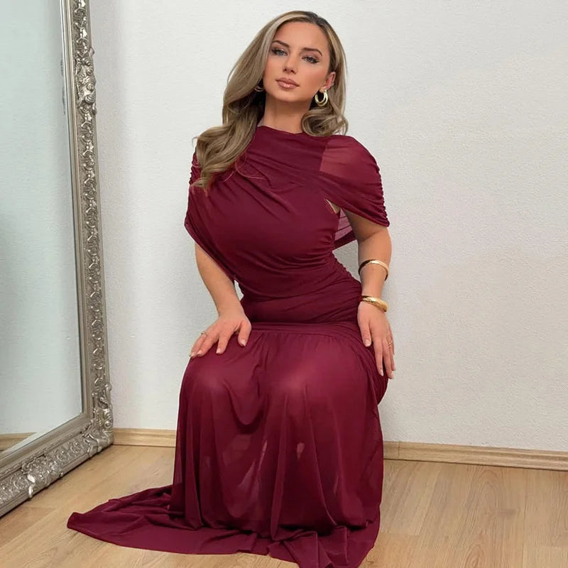 Woman in a burgundy evening gown sitting in front of a mirror.