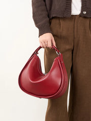Hand holding a red leather hobo bag
