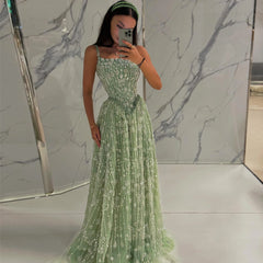 Woman in a green evening gown standing in front of a marble wall.