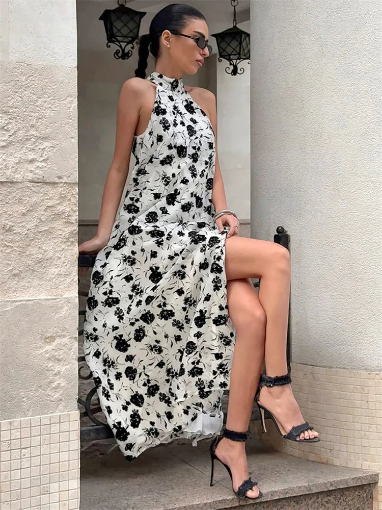 Woman in a black and white floral dress sitting on a stone step.