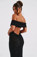Woman wearing a black off-shoulder dress with a lace detail on a white background
