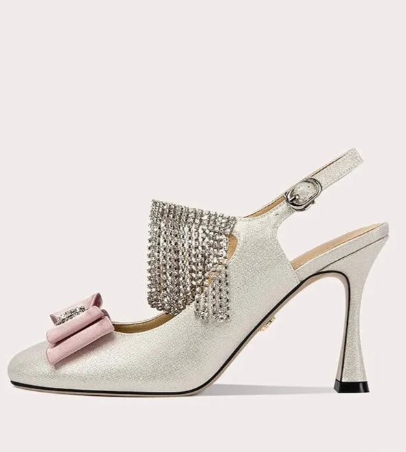 High-heeled shoe with decorative bow and tassel on a white background