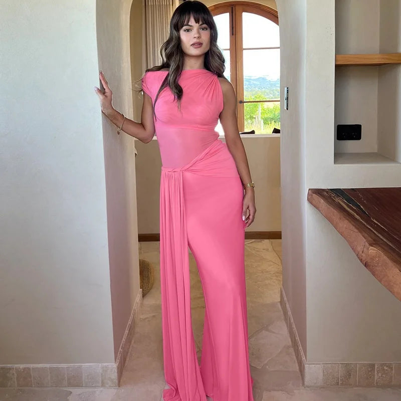 Woman in a pink dress standing in a room with a window in the background