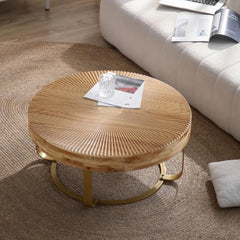 Round carved wooden coffee table with gold metal legs in a modern room