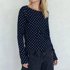 Person wearing a navy blue long-sleeve top with white polka dots against a plain background