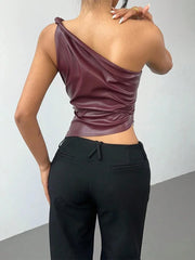 Person wearing a burgundy one-shoulder top and black pants against a plain background