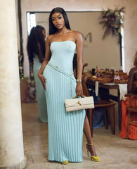 Woman in a light blue strapless dress with a beige handbag in an indoor setting.