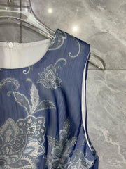 Blue dress with white paisley pattern on a hanger against a gray marble background