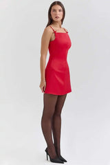 Woman wearing a red dress and black tights on a white background