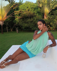 Woman wearing a blue ruched mesh mini dress with halter neckline.