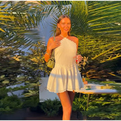 Woman in a white dress standing outdoors with palm trees in the background
