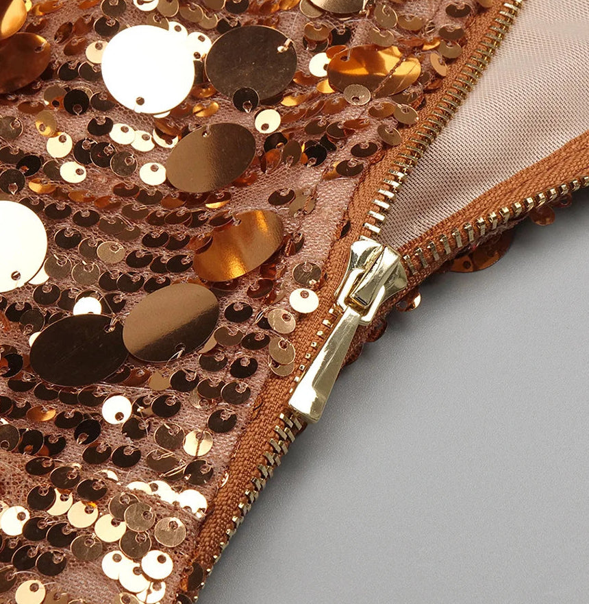 Close-up of a rose gold sequin pouch with a gold zipper on a gray background