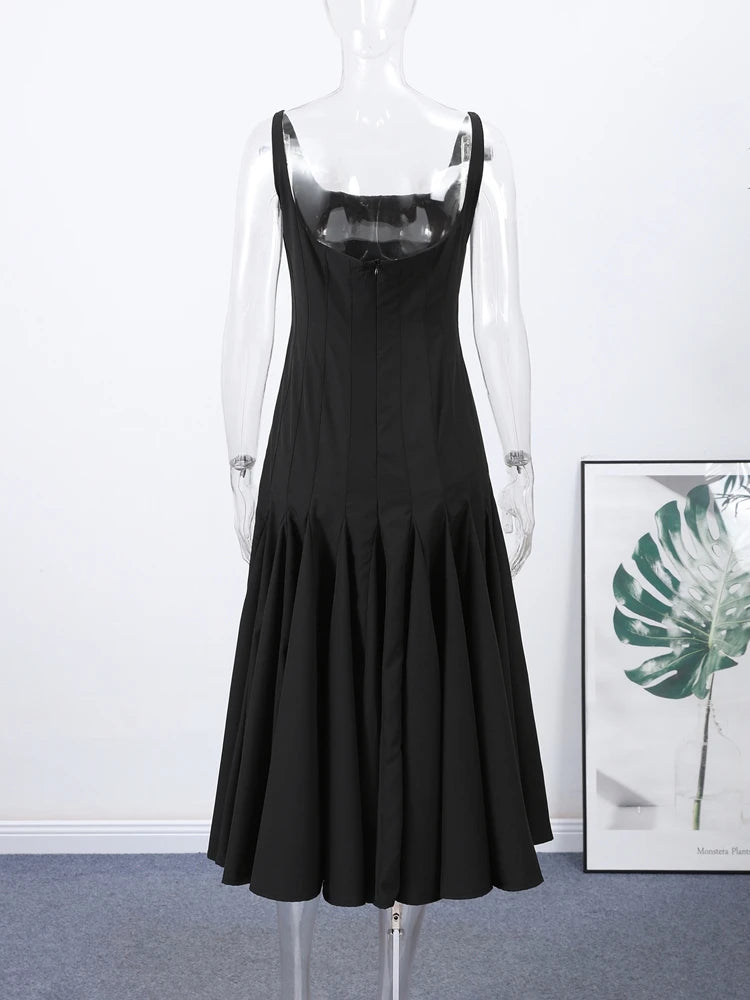 Black dress on a mannequin with a white wall and framed picture in the background
