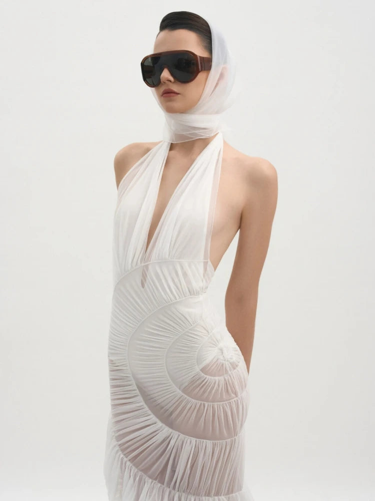 Woman wearing a white dress with a deep neckline and sheer overlay 