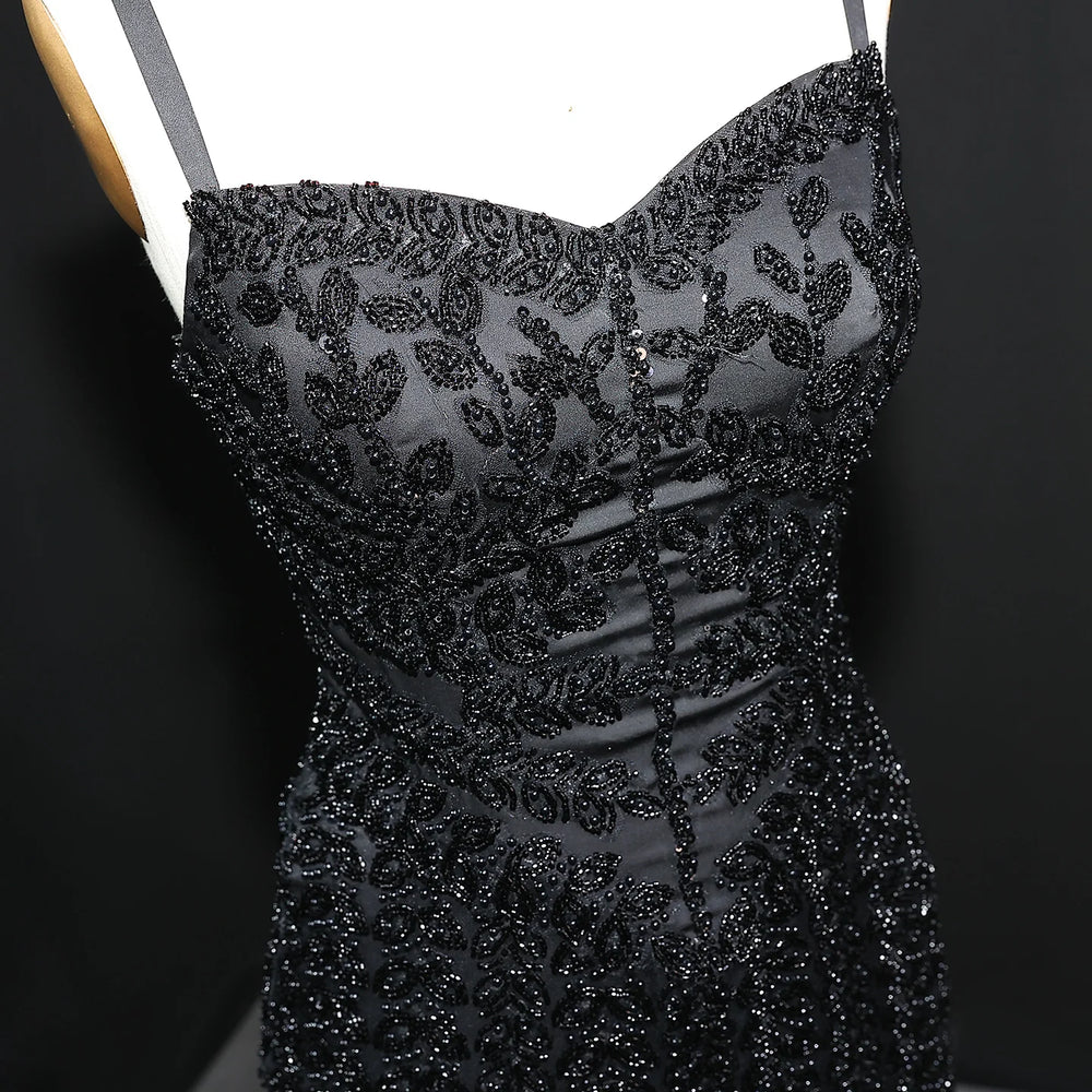 Black beaded dress on a mannequin against a dark background