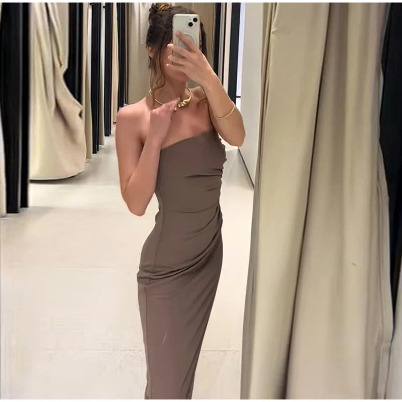 Woman taking a mirror selfie wearing a brown one-shoulder dress in a fitting room.
