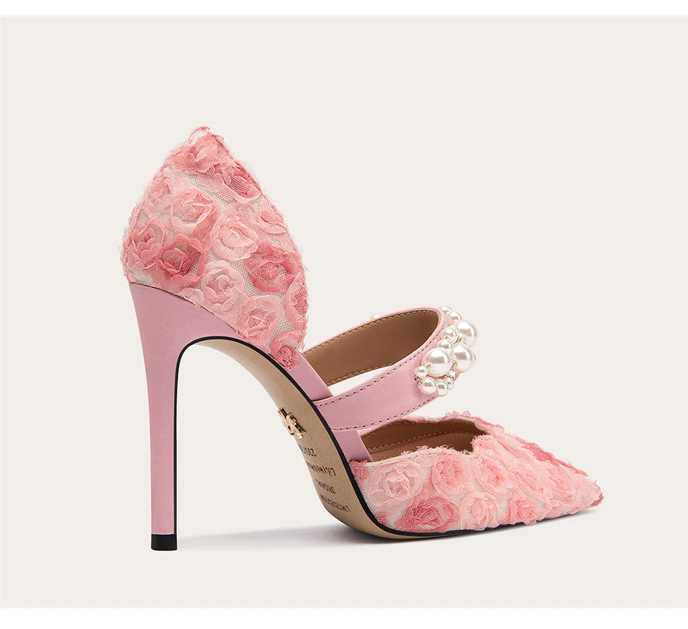 Pink lace high-heeled shoe with floral design on a light gray background