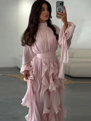 Woman wearing a pink ruffled dress taking a mirror selfie.