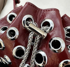 Close-up of a red leather boot with silver eyelets and chain detail.