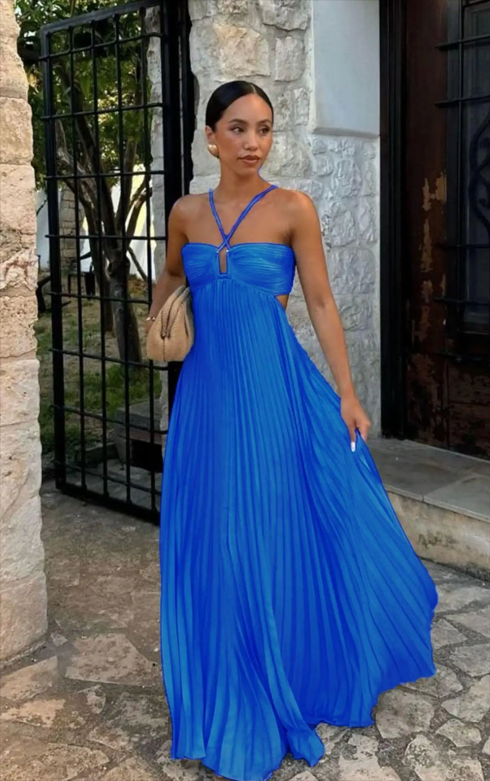 Woman in a blue dress standing outdoors near a stone building.