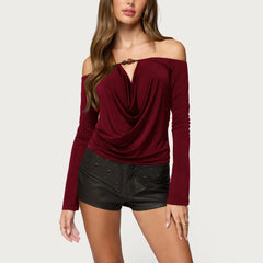 Woman wearing a burgundy off-shoulder top and black shorts on a white background
