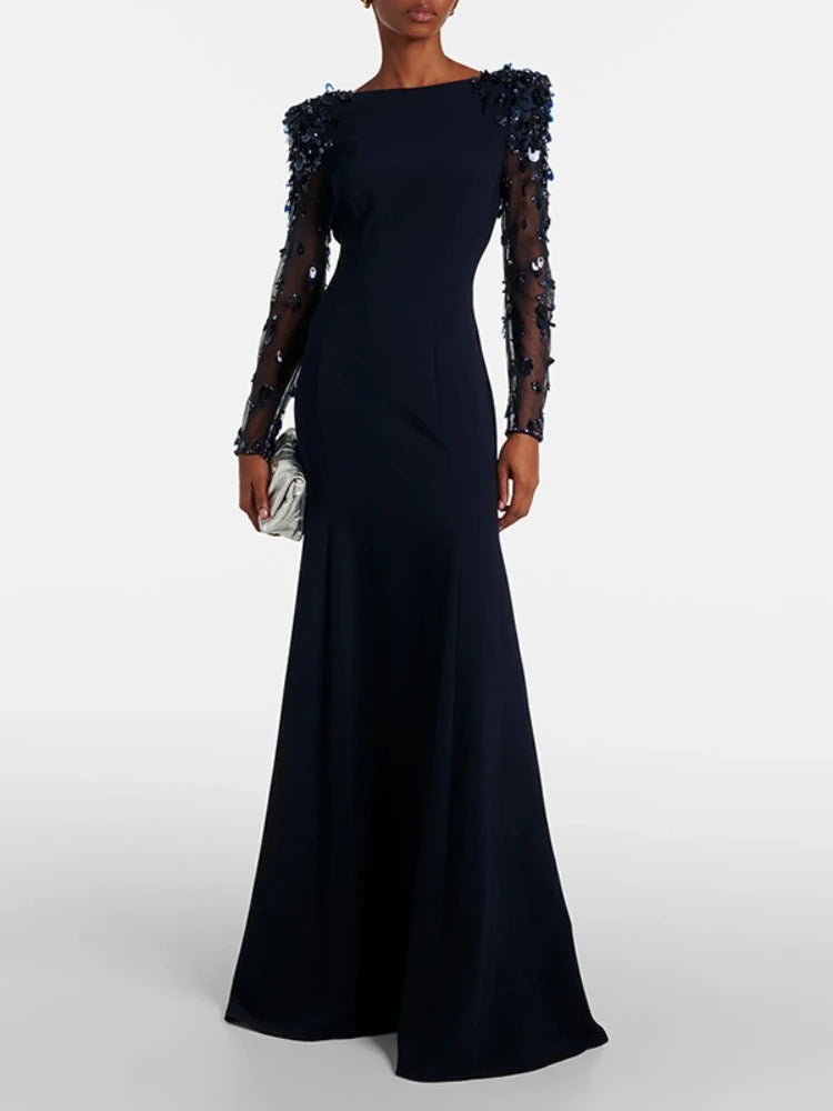 Black evening gown with sheer sleeves and bead details on a white background