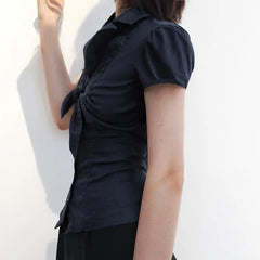Person wearing a black short-sleeve shirt with a knot detail on a white background