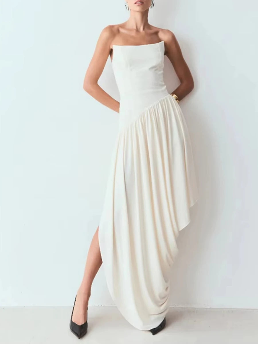 Woman wearing a strapless white dress with a high slit on a plain background