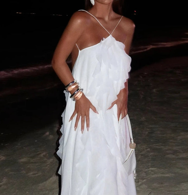 Woman wearing a white dress with ruffled details on a dark background