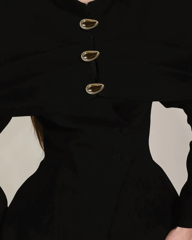 Close-up of a black coat with gold buttons on a neutral background