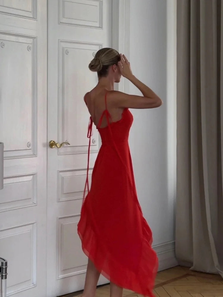 Woman in a red dress standing in a room with white walls and a door.