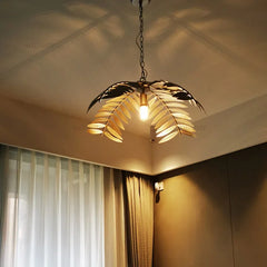 A dramatic iron palm leaf chandelier hanging in a modern dining room with natural light streaming in. D