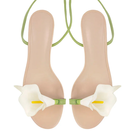 Beige sandals with white floral straps on a white background
