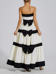 Woman wearing a strapless dress with black bows on a plain background