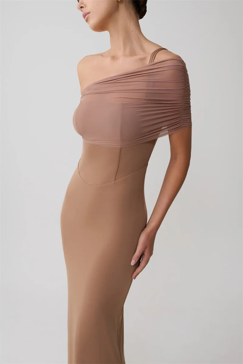 Woman wearing a one-shoulder brown dress on a plain background
