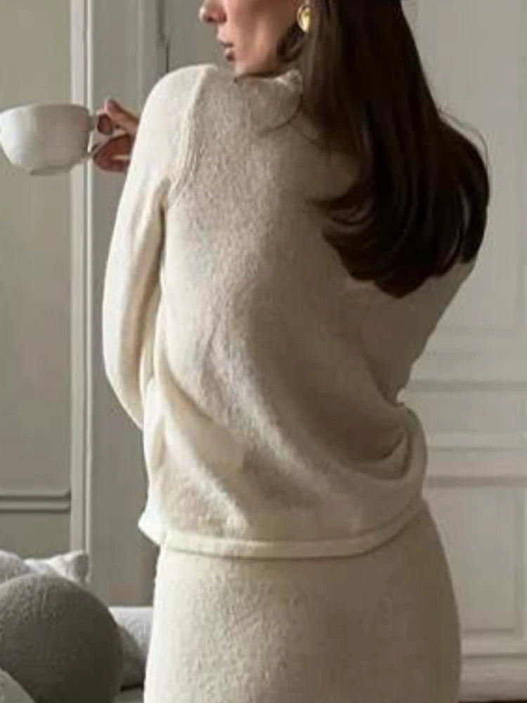 Woman in a beige outfit holding a cup against a neutral background