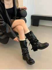 Person wearing black knee-high boots sitting on a chair indoors.
