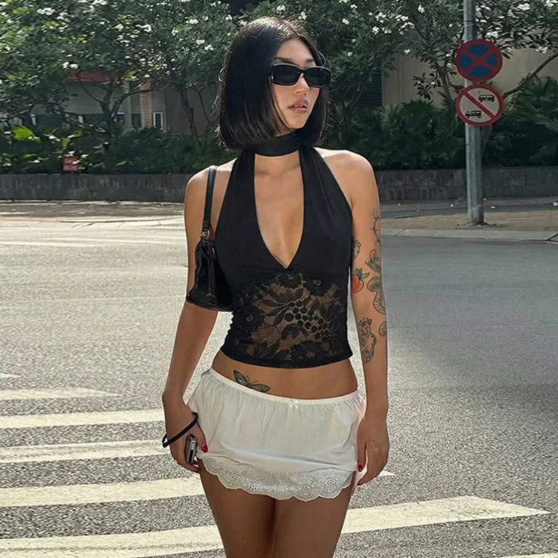 Woman wearing a black lace top and white shorts on a street.