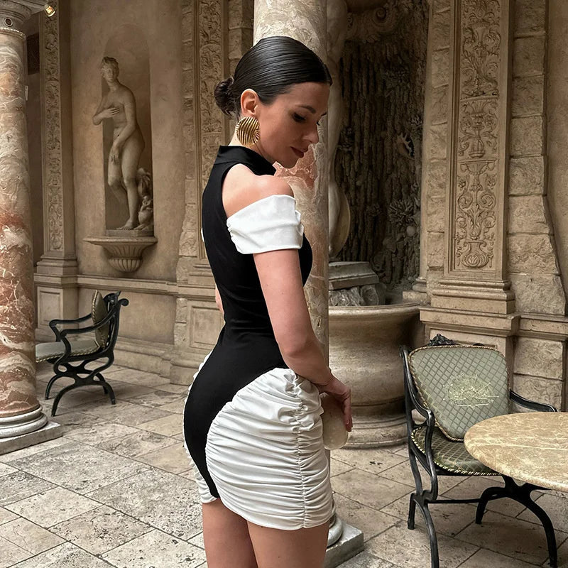 Woman in a black and white dress standing in an ornate outdoor setting.