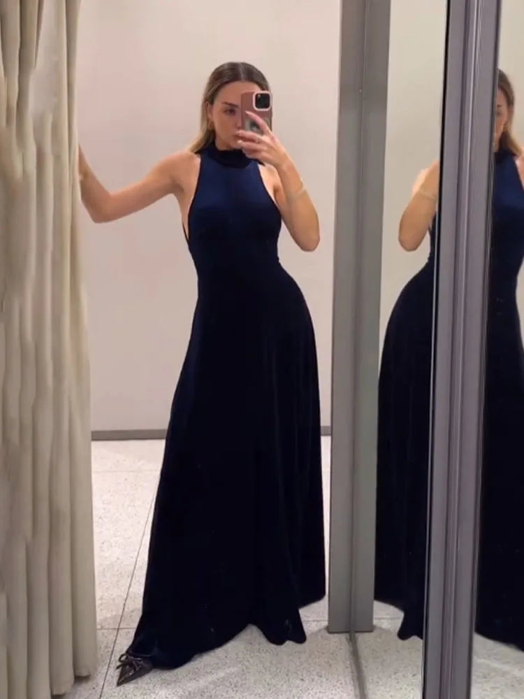 Woman wearing a black evening gown taking a mirror selfie.